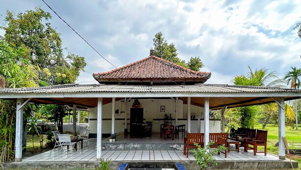 A covered outdoor area with a tiled floor, wooden furniture, and a tiled roof. - Cozzy HEPI Bungalo Lovina Singaraja Bali (Buleleng)