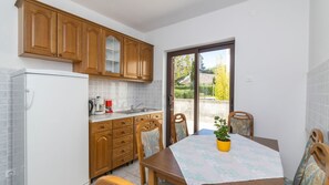 Une cuisine de taille réduite, dotée de meubles en bois, d’un réfrigérateur, d’un évier et d’une table à manger avec des chaises.