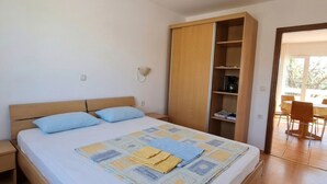 Een slaapkamer met een bed, een garderobe en uitzicht op een buitenruimte.