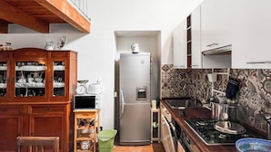 Une cuisine avec un plafond en bois, un four encastré, un réfrigérateur et un coin repas comprenant une table et des chaises.