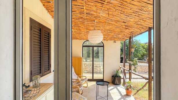 Une pièce avec un plafond en bois, un luminaire suspendu, une fenêtre donnant sur l’extérieur et une porte dotée d’une poignée.