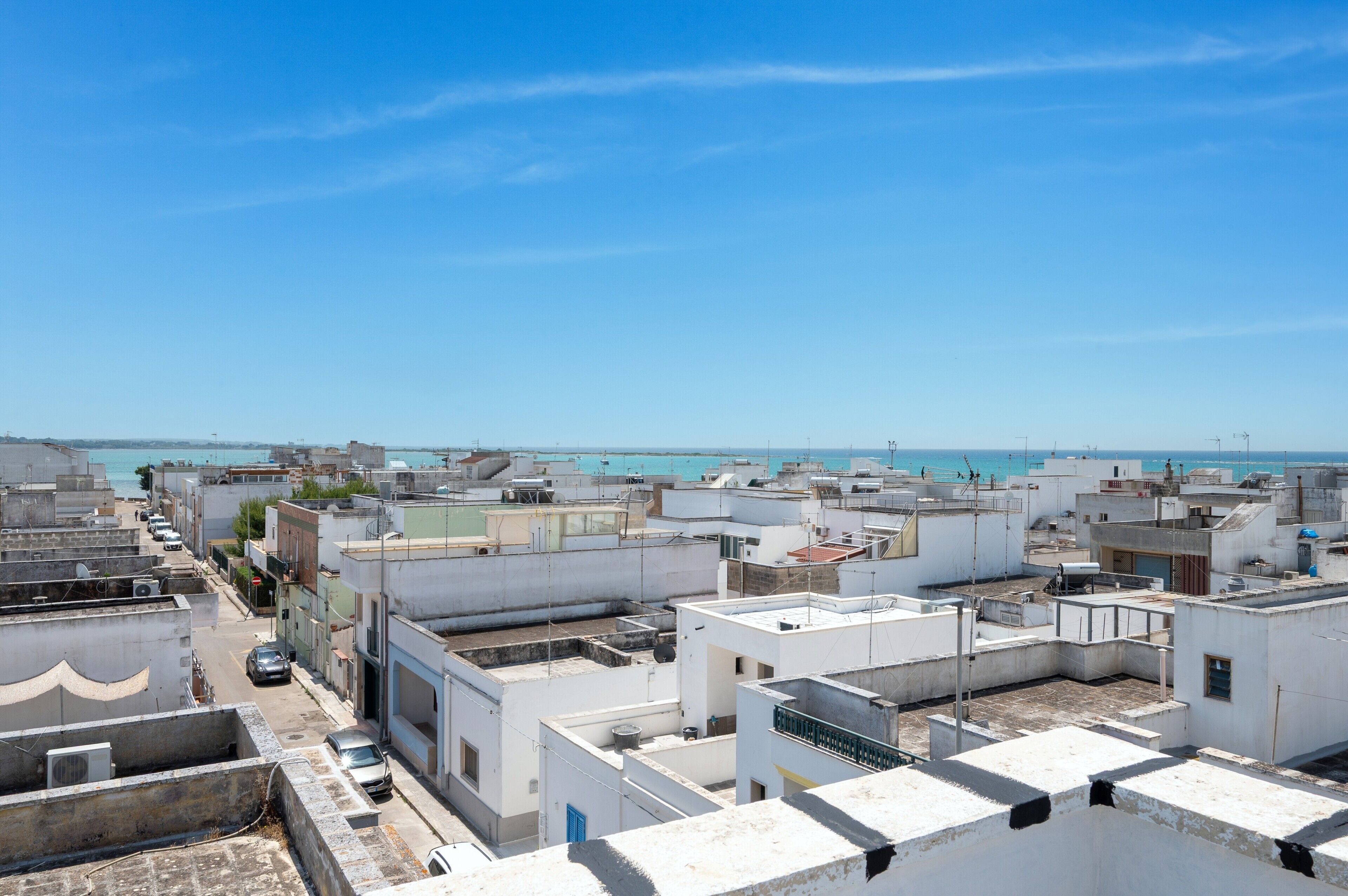Eine Küstenstadt mit weißen Gebäuden, blauem Himmel und Blick aufs Meer.