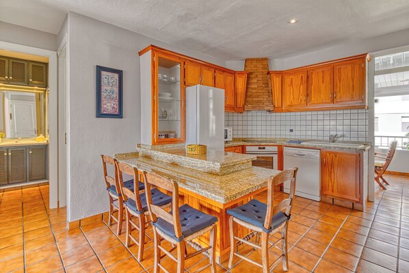 A kitchen with wooden cabinets, a granite countertop, and a built-in dishwasher.
