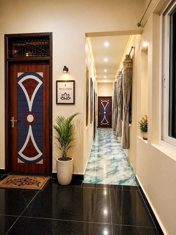 A hallway with a marble floor, a welcome sign, and a potted plant.