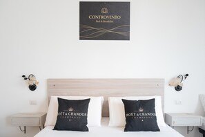 Ein Hotelzimmer mit einem Bett, zwei Nachttischen, einer Wandleuchte und einem gerahmten Schild über dem Bett.