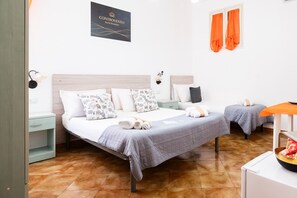 Ein Hotelzimmer mit zwei Betten, einem Nachttisch, einem an der Wand befestigten Schild und orangefarbenen Vorhängen.