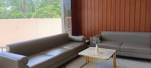 Ein modernes Wohnzimmer mit zwei Sofas, einem kleinen Tisch und Blick auf Grünflächen.