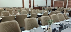 A conference room with multiple tables and chairs, equipped with glassware and napkins.