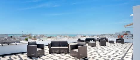 A rooftop terrace with outdoor seating and a cityscape view.