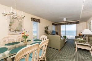 Ein Zimmer mit Esstisch, Stühlen, einer Couch, einem Fernseher und Blick auf den Ozean.