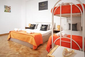 Ein Hotelzimmer mit zwei Betten, davon ein Etagenbett, orangefarbener Bettwäsche und Zierkissen.