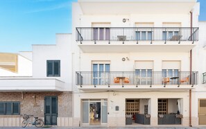 Un edificio a più piani con balconi, una bicicletta e un portone con una finestra.