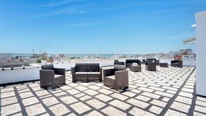 Terraza en la azotea con mobiliario exterior y vistas panorámicas de la ciudad.