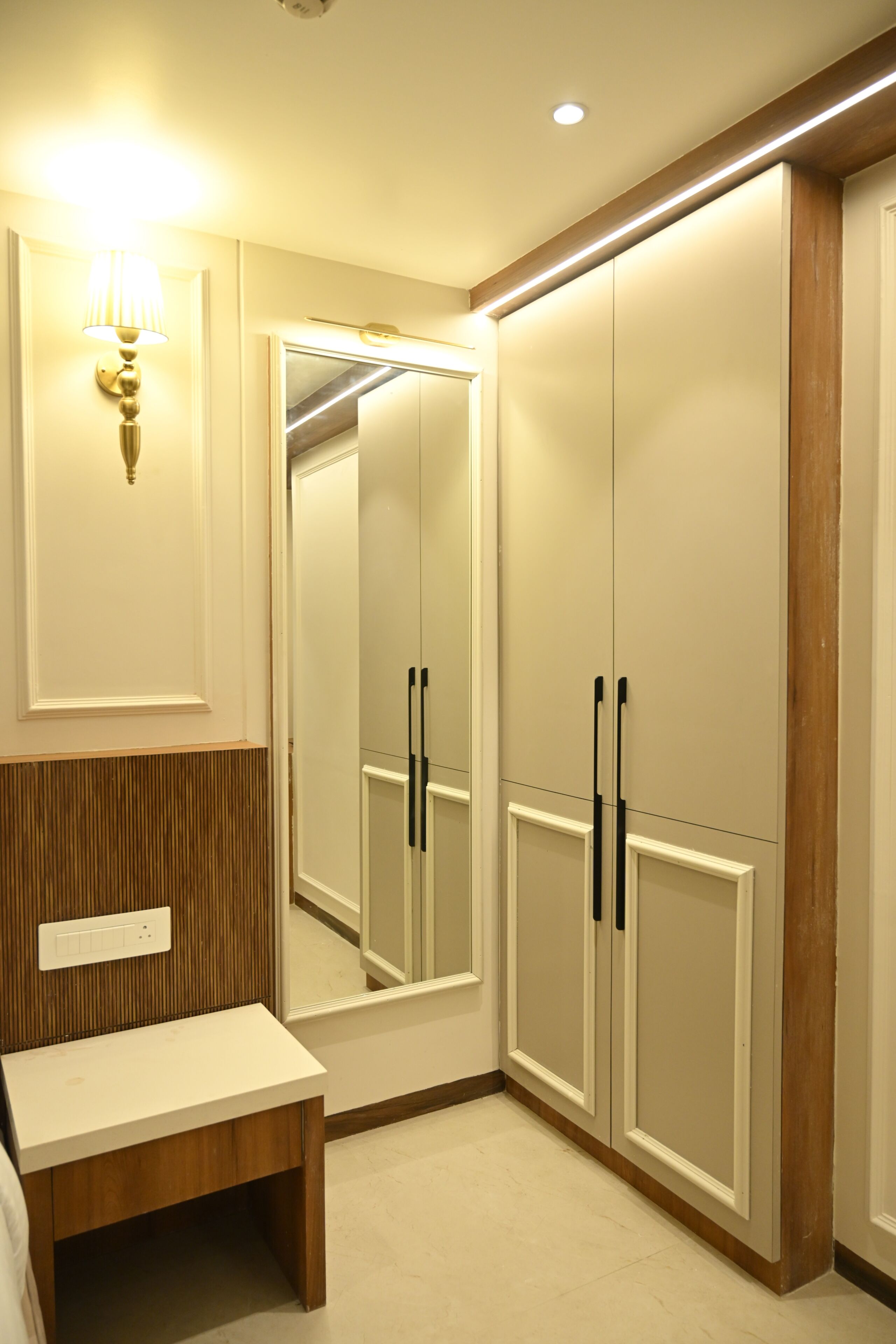 Un baño con espejo, tocador y un banco de madera.