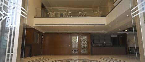 A spacious lobby with a high ceiling, a reception desk, and a patterned floor.