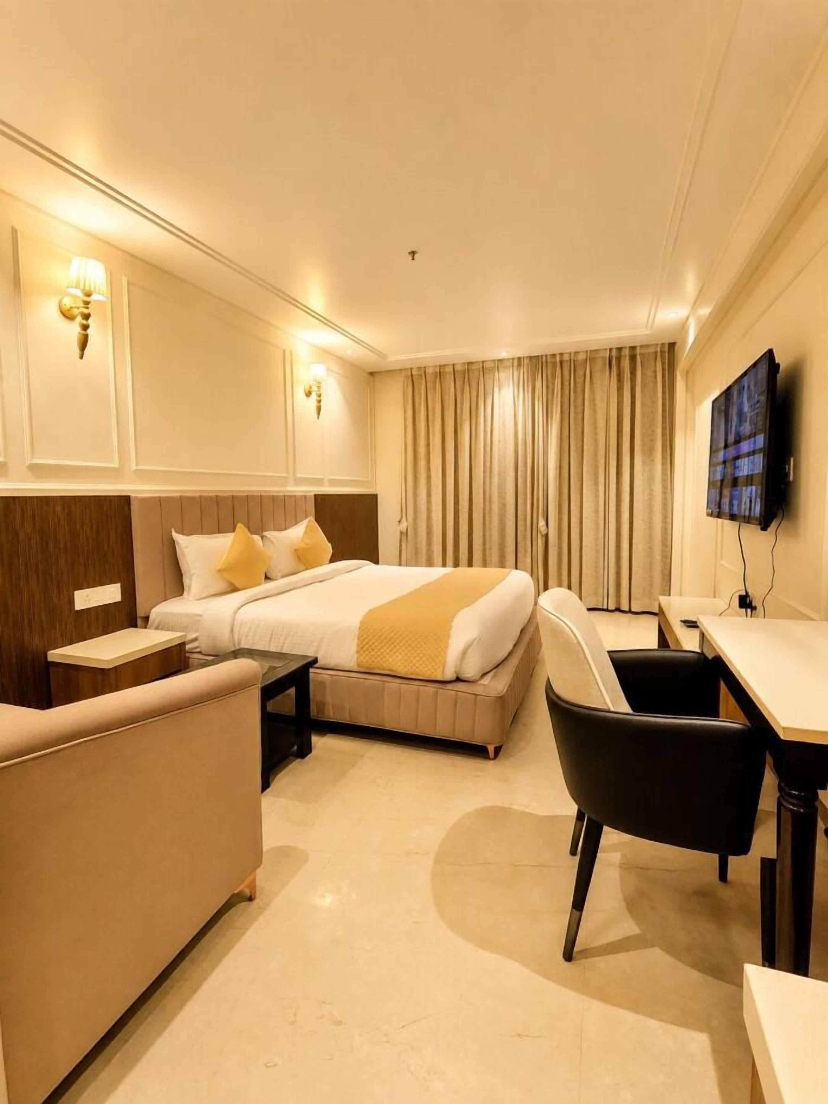 A hotel room with a bed, a desk, a chair, and a television.