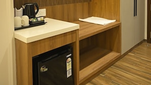 A compact kitchen with a built-in refrigerator, a coffee maker, and a microwave on the counter. - ANANTA KASHI HOTEL (Varanasi)