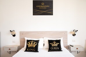 Ein Hotelzimmer mit einem Bett, zwei Nachttischen, einem an der Wand befestigten Schild und dekorativen Wandleuchten.