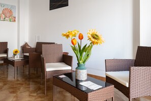 Een receptie met rieten meubels, een vaas met zonnebloemen en een kunstwerk aan de muur.