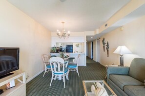 Ein Hotelzimmer mit Fernseher, Essbereich, Küchenzeile und einer Couch.