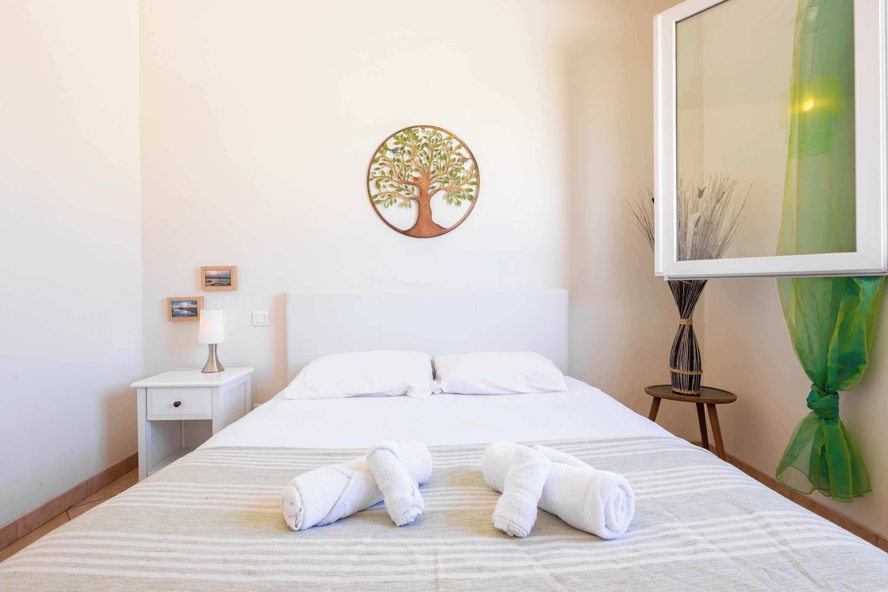 Une chambre d’hôtel comprenant un lit, des oreillers, une table de chevet avec une lampe, un tableau encadré, un élément de décoration murale et un miroir.