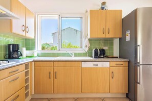 Eine Küche mit Holzausstattung, einem Edelstahlkühlschrank, einem Fenster mit Blick und einem Bosch Geschirrspüler.