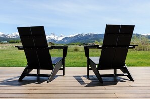 Two black Adirondack chairs on a wooden deck with a view of snow-capped mountains. - Modern Teton View Home in Driggs w/AC (Driggs)