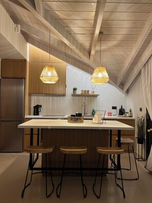 A modern kitchen with a central island, pendant lights, and wooden cabinetry.