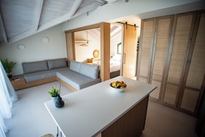 Um interior moderno com uma ilha de cozinha, um sofá cinza e uma porta deslizante de madeira.