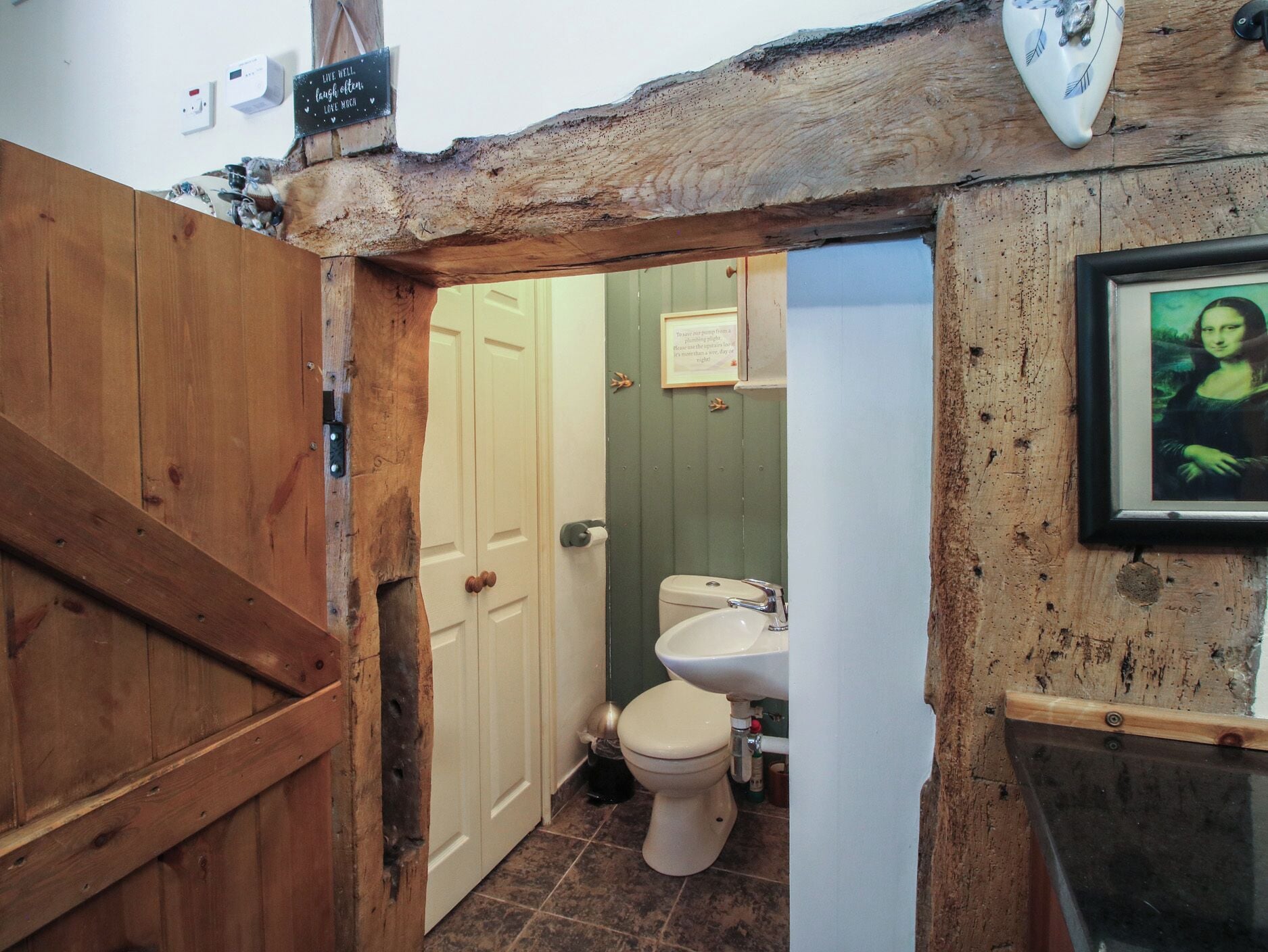 A rustic bathroom with a wooden door, a toilet, and a sink.