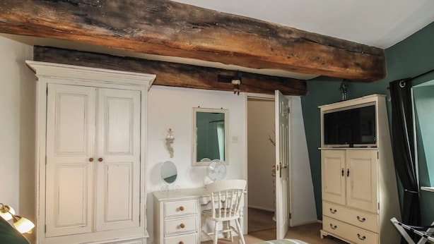 A bedroom with a large bed, a dresser, a vanity with a mirror, a chair, and a wardrobe. - Hadley Park Windmill (Telford)