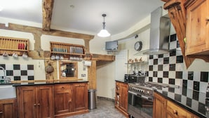 A kitchen with wooden cabinets, a stainless steel stove, and a checkered backsplash. - Hadley Park Windmill (Telford)