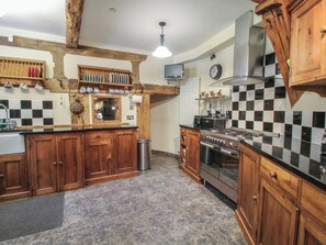 Eine Küche mit Holzausstattung, einem Edelstahlherd und einer karierten Spritzschutzwand.