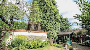 A garden with a brick wall, a wooden bench, and a gazebo. - Hadley Park Windmill (Telford)