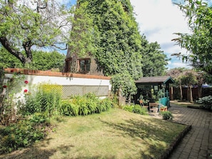 Ein Garten mit einer Ziegelmauer, einer hölzernen Bank und einem Pavillon.