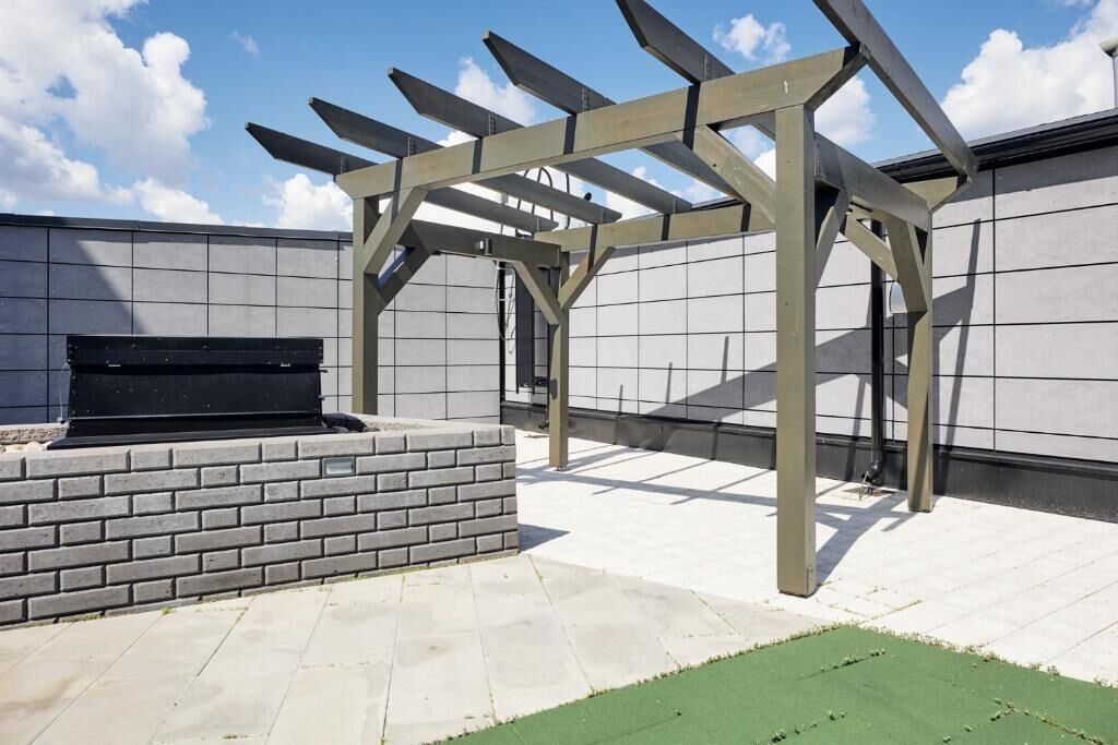 An outdoor patio area with a pergola structure, a brick planter, and a flat roof.