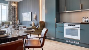 Una cocina moderna con horno empotrado, un comedor con mesa y sillas redondas, y un ventanal grande.