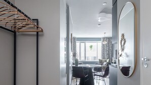 Un interior moderno con una escalera, un comedor con sillas, un espejo y vistas por una ventana.