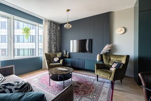Een moderne woonkamer met een groot raam, een flatscreen televisie en een kamerkleed met een patroon.