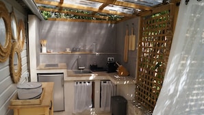 A compact kitchen with a sink, a small refrigerator, wooden utensils, and a coffee maker.