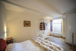 Ein Schlafzimmer mit Bett, Schrank, Schreibtisch und Fenster.