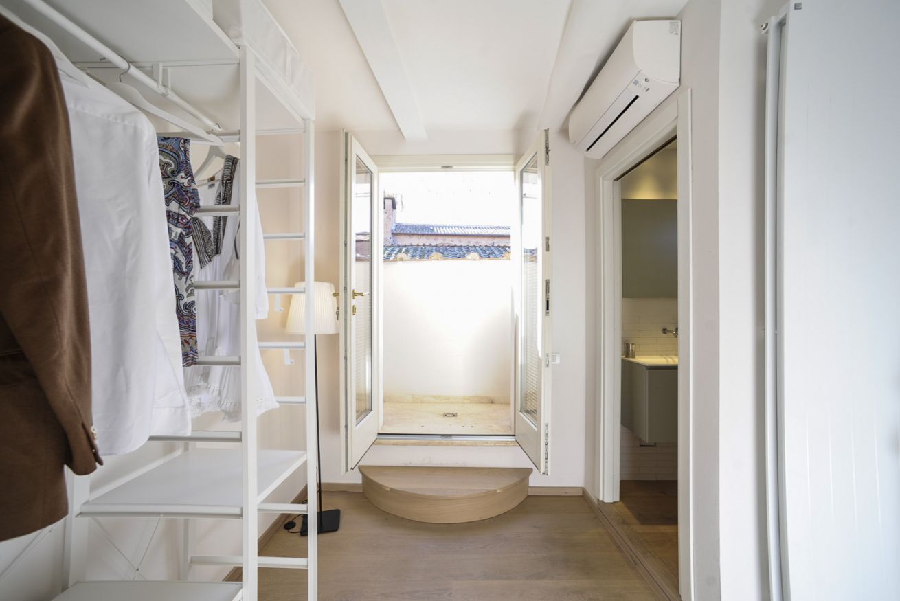 Un pasillo estrecho con una puerta de madera que da a un balcón con techo de tejas tradicionales.