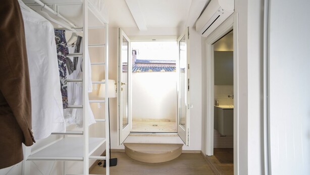 Een smalle gang met een houten deur die uitkomt op een balkon met een traditioneel betegeld dak.