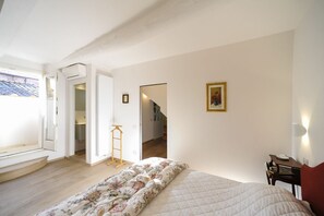 Ein Schlafzimmer mit Bett, Kleiderschrank, Schreibtisch und Fenster.