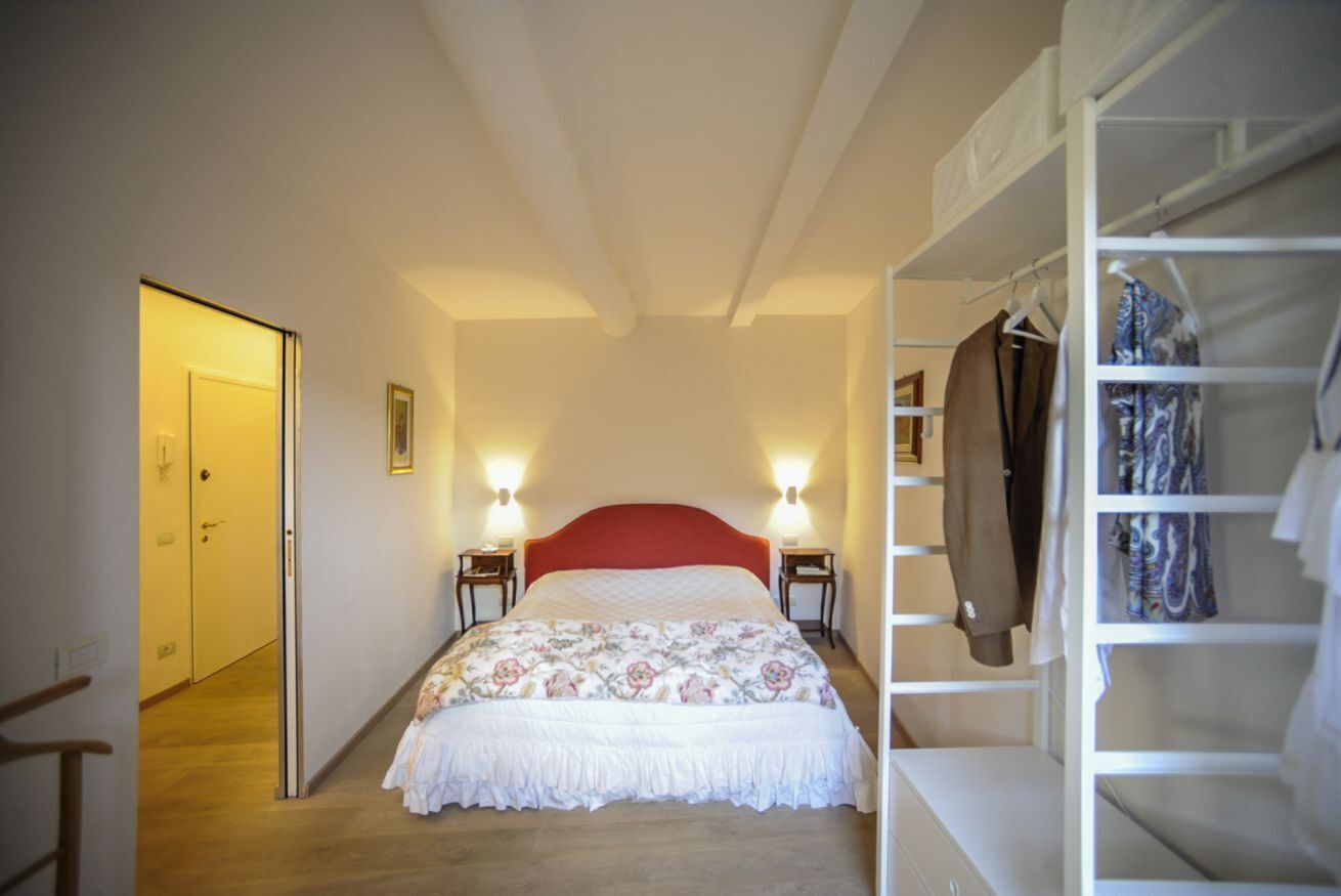 Une chambre à coucher comprenant un lit, des lampes de chevet, une armoire et une porte donnant sur une autre pièce.