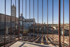 Blick auf ein historisches Gebäude mit einem markanten Turm und einer Kuppel, aufgenommen durch ein Metallgitter.