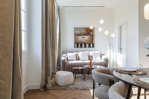 A modern living room with a sofa, ottoman, and dining table set for two. - Exceptional apartment in the heart of Nice (Nice)