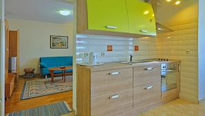 A modern kitchen with light wood cabinets, a built-in oven, and a sink. - Coastal Serene Stay in Umag (Umag)