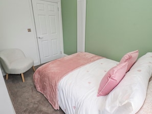 A bedroom with a bed, a chair, and a door. - Middle Cottage (Alnwick)
