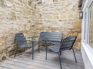 A stone wall, a wooden deck, and a table with chairs. - Middle Cottage (Alnwick)